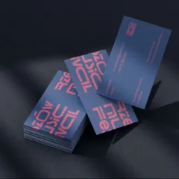 Stos wizytówek w kolorze granatowym z różowymi napisami, ułożonych na ciemnym tle z cieniem.