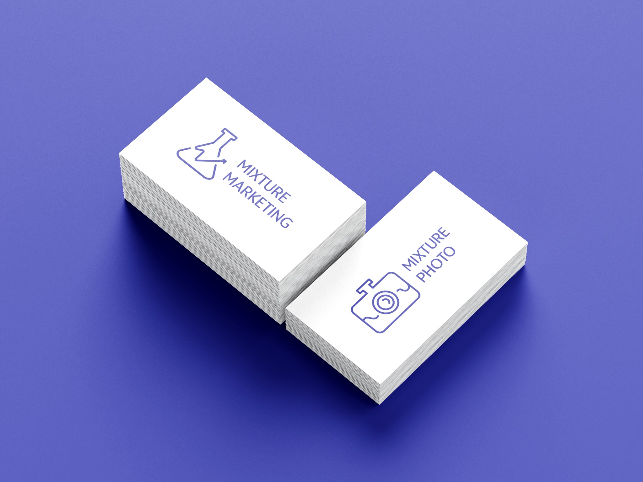 Dwa stosy białych wizytówek z niebieskimi ikonami i tekstem na niebieskim tle. Jeden stos z ikoną kolby i napisem 'Mixture Marketing', drugi z ikoną aparatu i napisem 'Mixture Photo'.