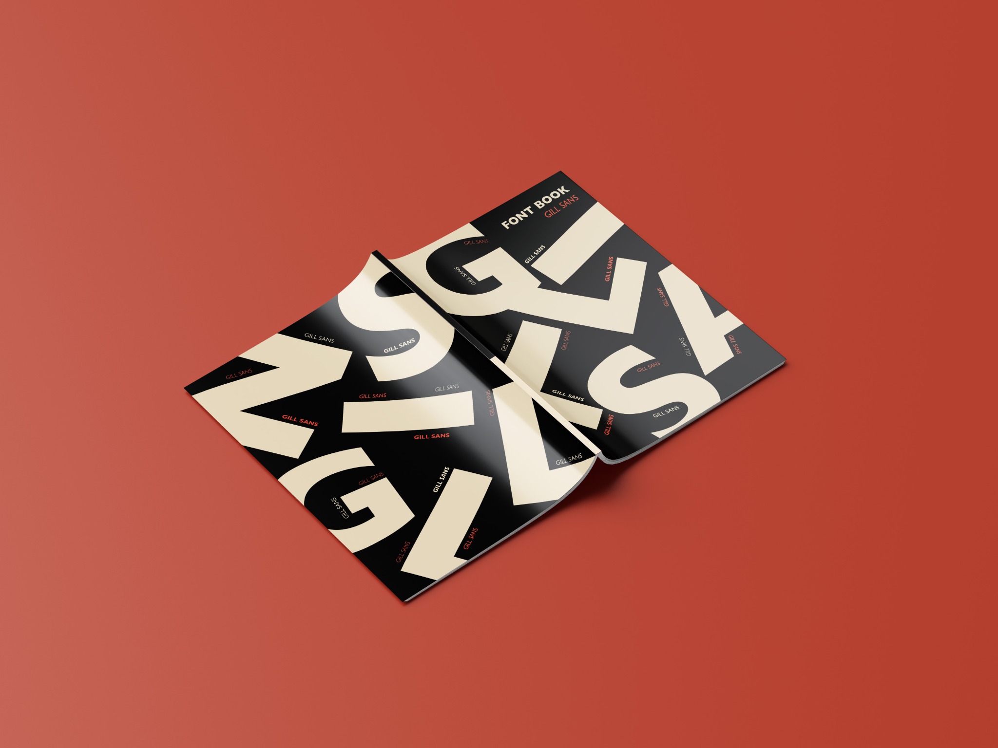 Otwarta książka z czarno-białym wzorem typograficznym 'Gill Sans' na okładce i stronach, leżąca na pomarańczowym tle.