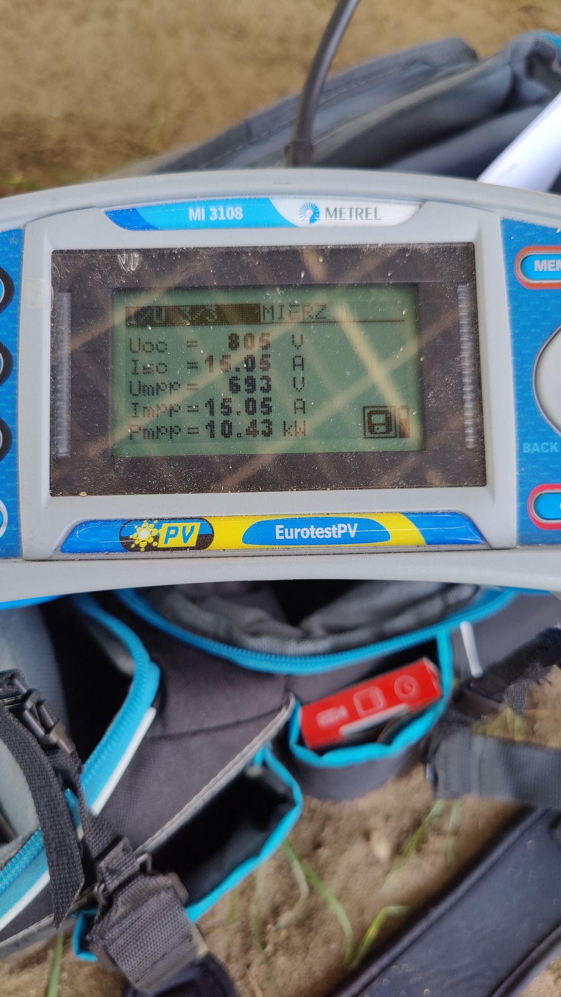 Miernik Metrel MI 3108 EurotestPV wyświetlający parametry elektryczne instalacji fotowoltaicznej: Uoc=805V, Isc=15.05A, Umpp=693V, Impp=15.05A, Pmpp=10.43kW, umieszczony na torbie narzędziowej.
