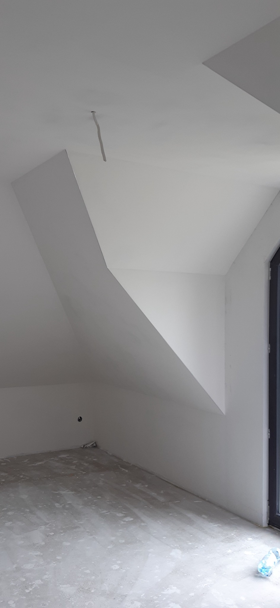 Poddasze po malowaniu na biało, widoczne skosy, kabel wystający z sufitu i zabezpieczona podłoga.