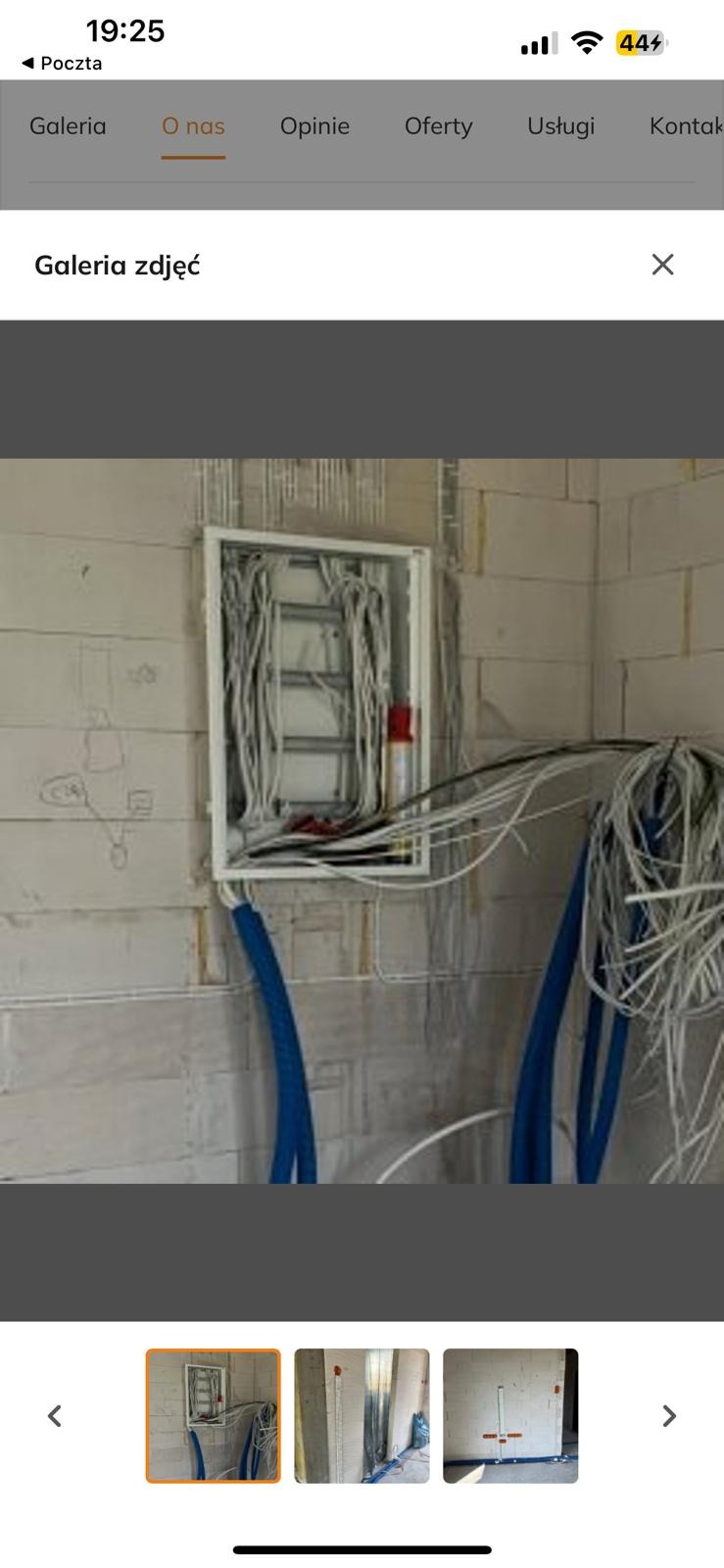 Rozdzielnica elektryczna w trakcie montażu na ścianie z betonu komórkowego, z widocznymi przewodami i niebieskimi rurkami instalacyjnymi.