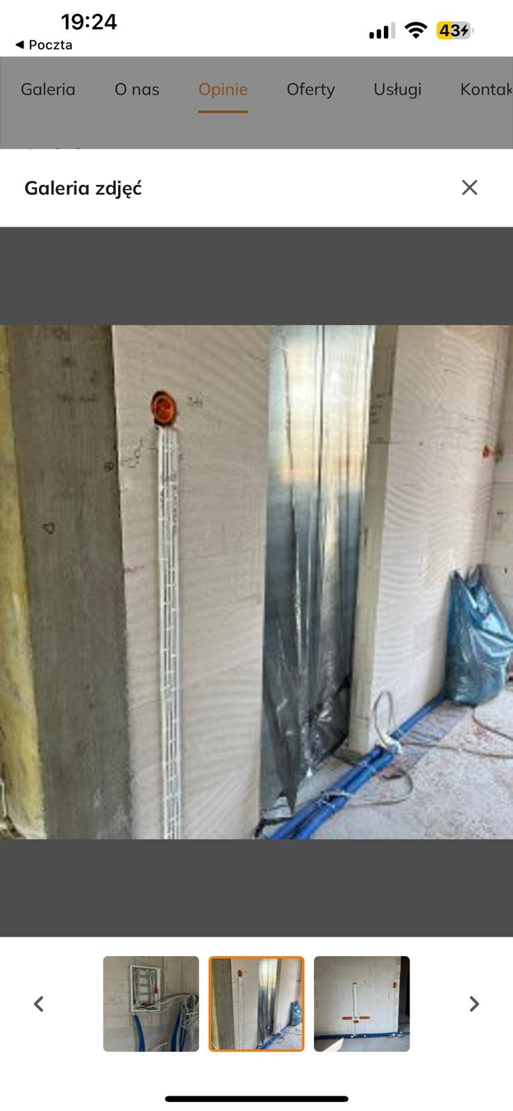 Ściana z zamontowaną puszką elektryczną i korytem kablowym w surowym stanie, przed wykończeniem. Widoczne niebieskie rury instalacyjne i folia ochronna.