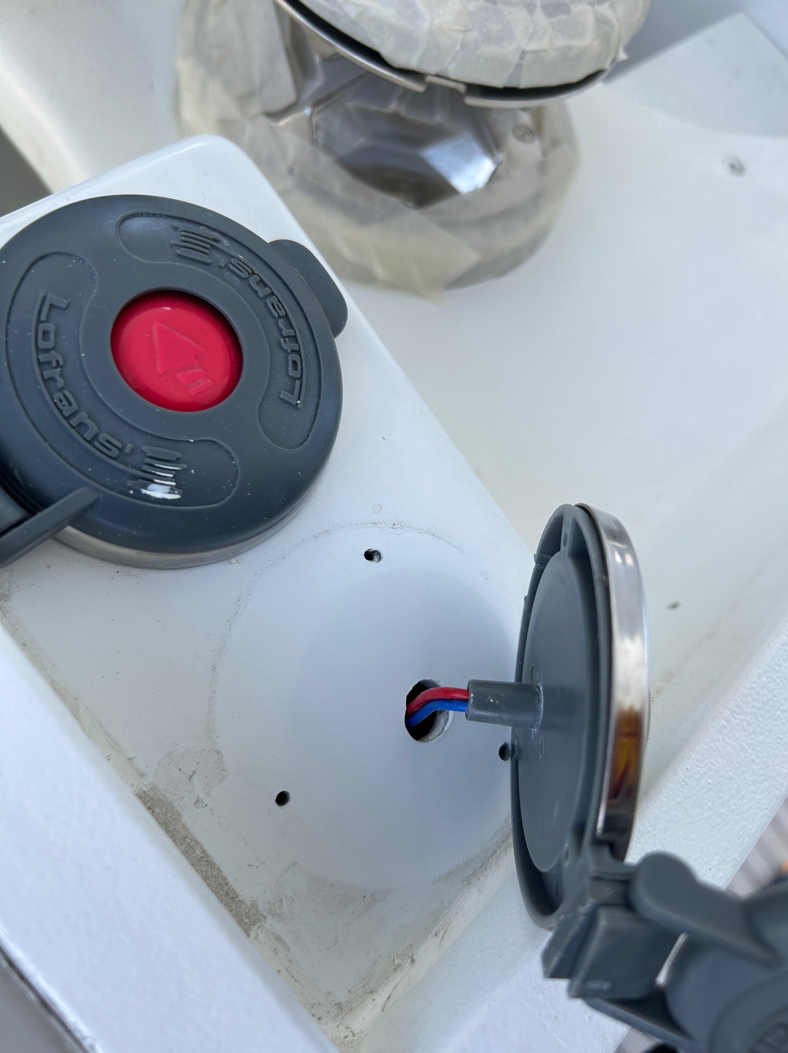 Montaż panelu sterowania z czerwonym przyciskiem i otwartą obudową z widocznymi przewodami na białej powierzchni.