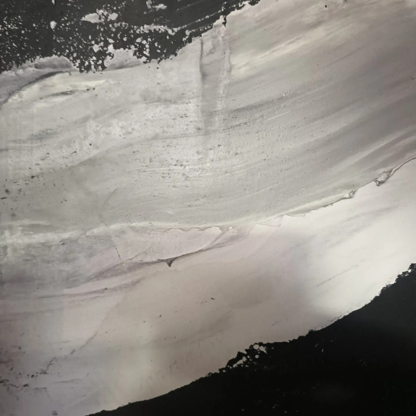 Świeżo nałożona, mokra warstwa szarej masy szpachlowej na ścianie, widoczne ślady po pacy i nierówności powierzchni.