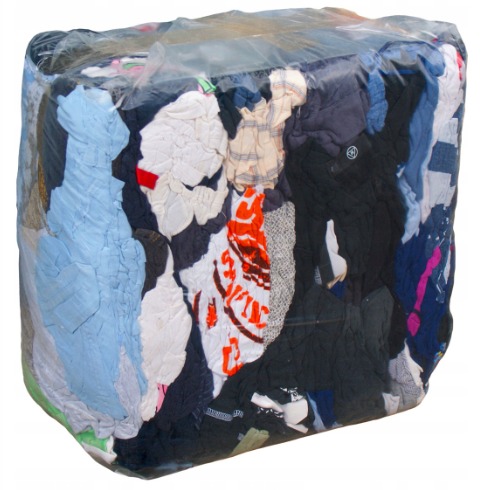 Sześcian sprasowanej odzieży, owinięty przezroczystą folią, ukazujący różnorodność faktur i kolorów tkanin.