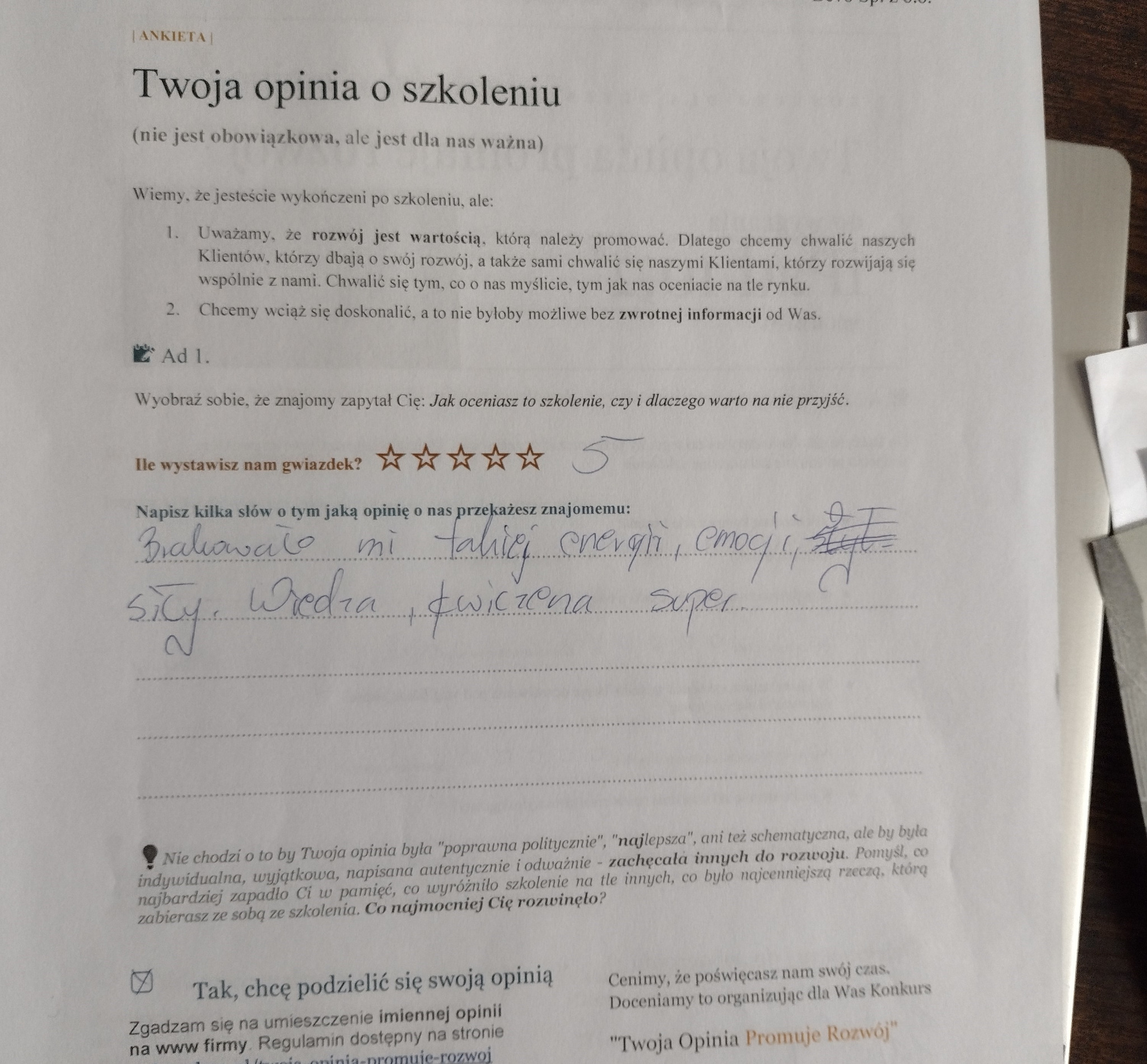Wypełniony formularz ankiety oceniającej szkolenie z pięcioma gwiazdkami i odręcznie napisaną opinią: 'Brakowało mi takiej energii, emocji, siły, wiedza, ćwiczenia, super'.