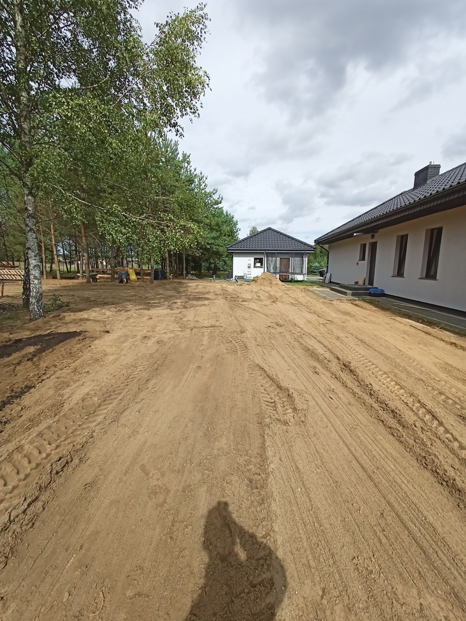 Ukształtowany teren wokół nowo wybudowanych domów jednorodzinnych z widocznymi śladami opon pojazdów budowlanych.