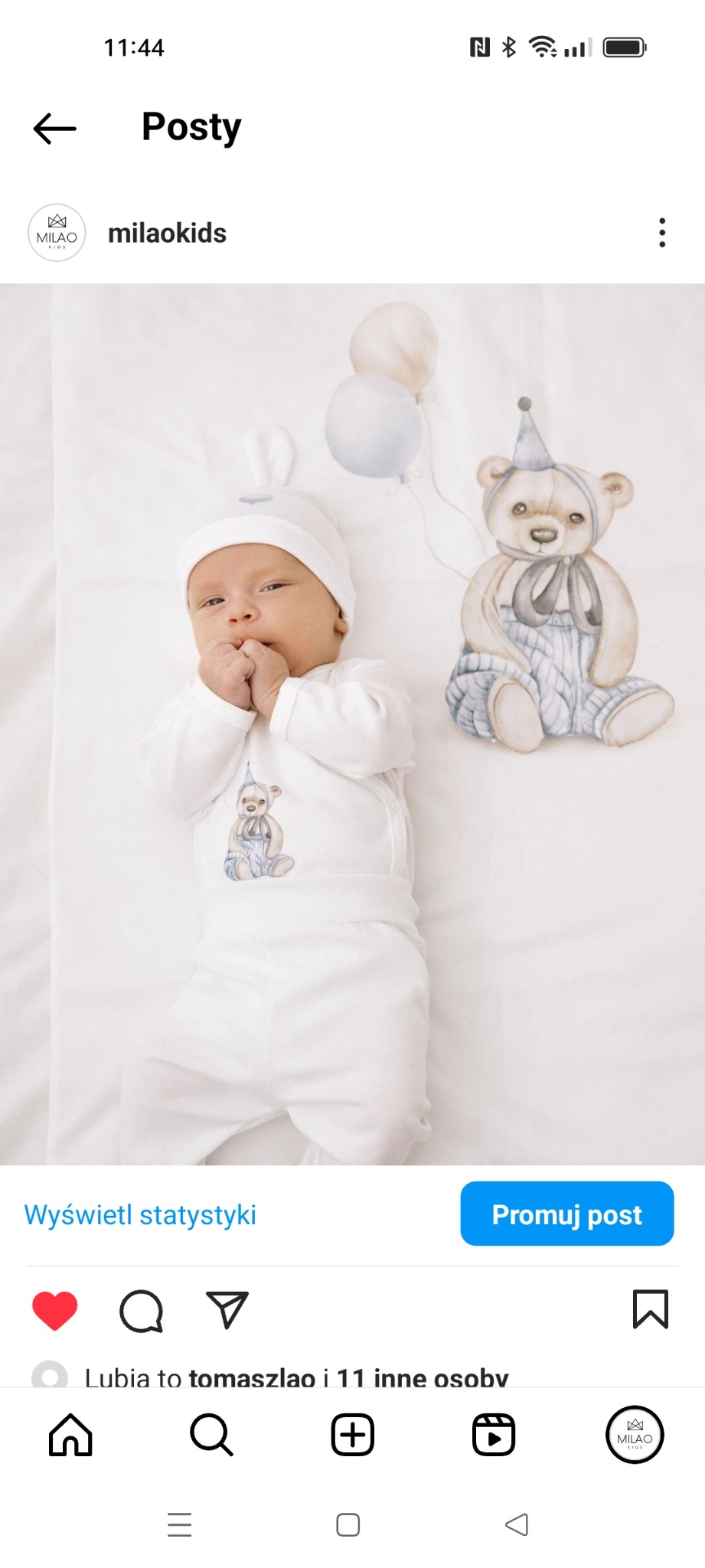 Noworodek w białym ubranku z motywem misia w Radomiu, leżący na białym tle obok ilustracji misia z balonami.