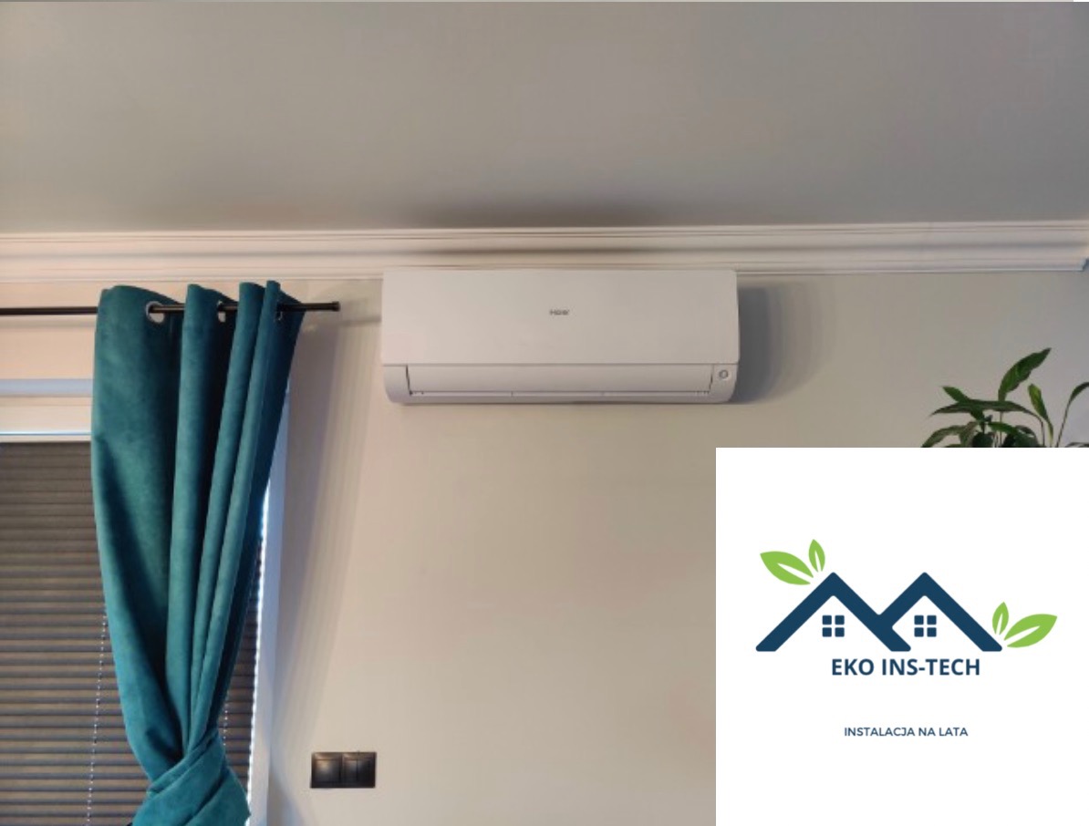 Biały klimatyzator Haier zamontowany na ścianie nad włącznikiem, obok zielonych zasłon i rośliny doniczkowej, z nałożonym logo firmy Eko Ins-Tech.