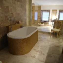 Luksusowa łazienka z wanną obłożoną mozaiką w odcieniach złota, marmurowa podłoga i ściany, szklana kabina prysznicowa w tle, eleganckie krzesło i zestaw szklanek na półce.