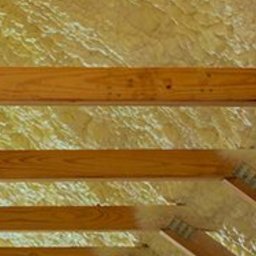 Skandi Pur - Poddasze z drewnianą konstrukcją więźby dachowej wypełnione jasną pianką izolacyjną, widoczne detale mocowania belek.