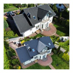 EKSPERT-TECH SŁAWOMIR ŚNIEŻEK - Zdjęcie z lotu ptaka przedstawia dom przed i po renowacji dachu. Po lewej stronie widoczny samochód i drabina oparta o ścianę, sugerujące prace renowacyjne.