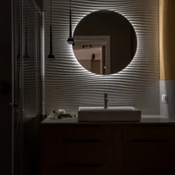 Nowoczesna łazienka z umywalką nablatową, okrągłym lustrem z podświetleniem LED i dekoracyjną ścianą z falistych paneli 3D. Minimalistyczne lampy wiszące.