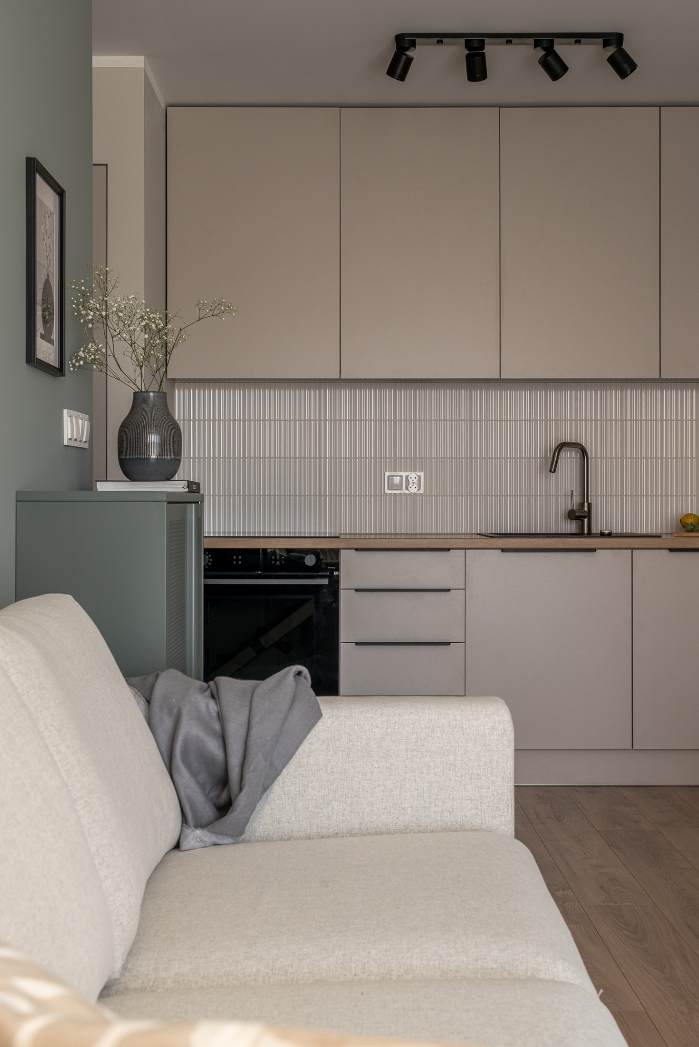 Stylowa kuchnia w odcieniach beżu we Wrocławiu. Uwagę przykuwają płytki na ścianie nad blatem z delikatnym wzorem i minimalistyczna armatura.