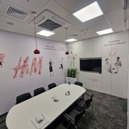PPHU MUFA - Jasne biuro z podłużnym stołem konferencyjnym, czarnymi krzesłami, ścianami z inspirującymi napisami i grafikami w odcieniach czerwieni, oraz wiszącymi lampami z czerwonymi kloszami.