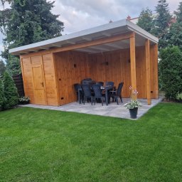 PPHU MUFA - Drewniana altana z przyległym pomieszczeniem gospodarczym, wyposażona w stół i krzesła, ustawiona na wybrukowanym tarasie w zadbanym ogrodzie.