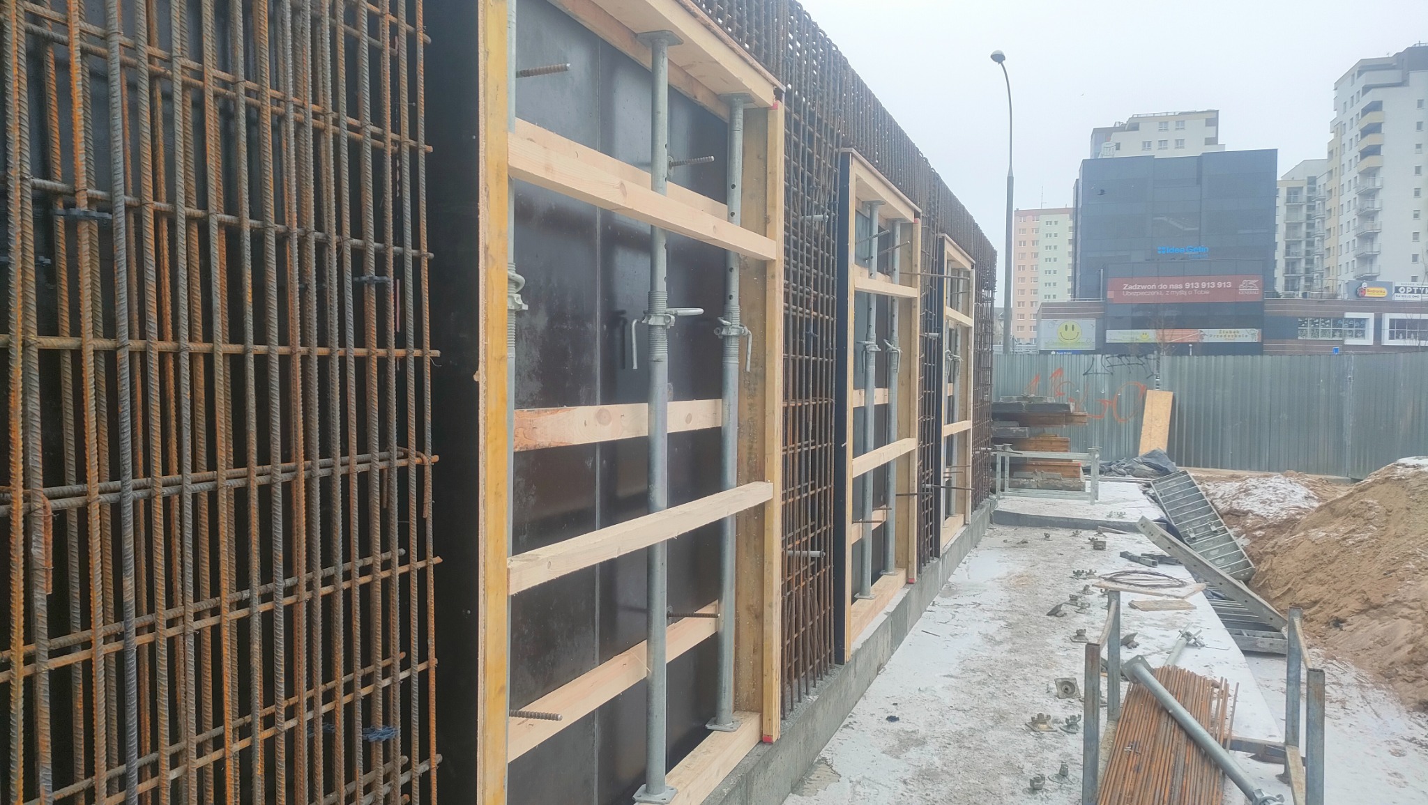 Zbrojenie i szalunek pod fundament w Olsztynie, widoczne pręty zbrojeniowe i drewniane elementy konstrukcji szalunkowej.