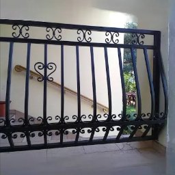 Mmetal - Czarna, ozdobna barierka metalowa z motywem serca na tle jasnych schodów z drewnianą poręczą i widokiem na zieleń ogrodu.