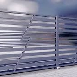 Mmetal - Nowoczesna brama przesuwna z metalowymi, poziomymi profilami o asymetrycznym układzie, wykończona w kolorze szarym, na tle jasnej elewacji.