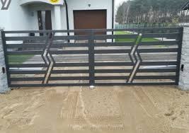 Nowoczesna, dwuskrzydłowa brama posesyjna w kolorze antracytowym z poziomymi przęsłami i geometrycznym wzorem zygzaków, zamontowana na słupkach z szarego kamienia, z widocznymi napędami po bokach.