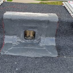 Zdzisław Głowacki - Uszczelnienie kominka wentylacyjnego na dachu pokrytym papą, z widocznymi elementami mocującymi instalację solarną.