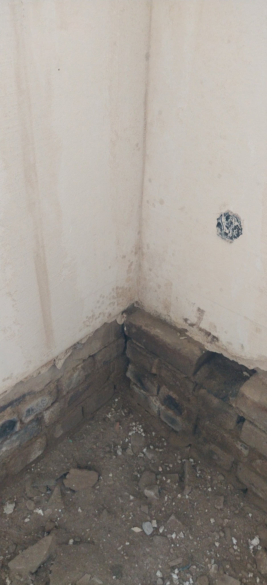 Fragment ściany z instalacją elektryczną i fundamentem z cegły w trakcie prac wykończeniowych w Gryficach. Widoczne ślady wilgoci na ścianie.