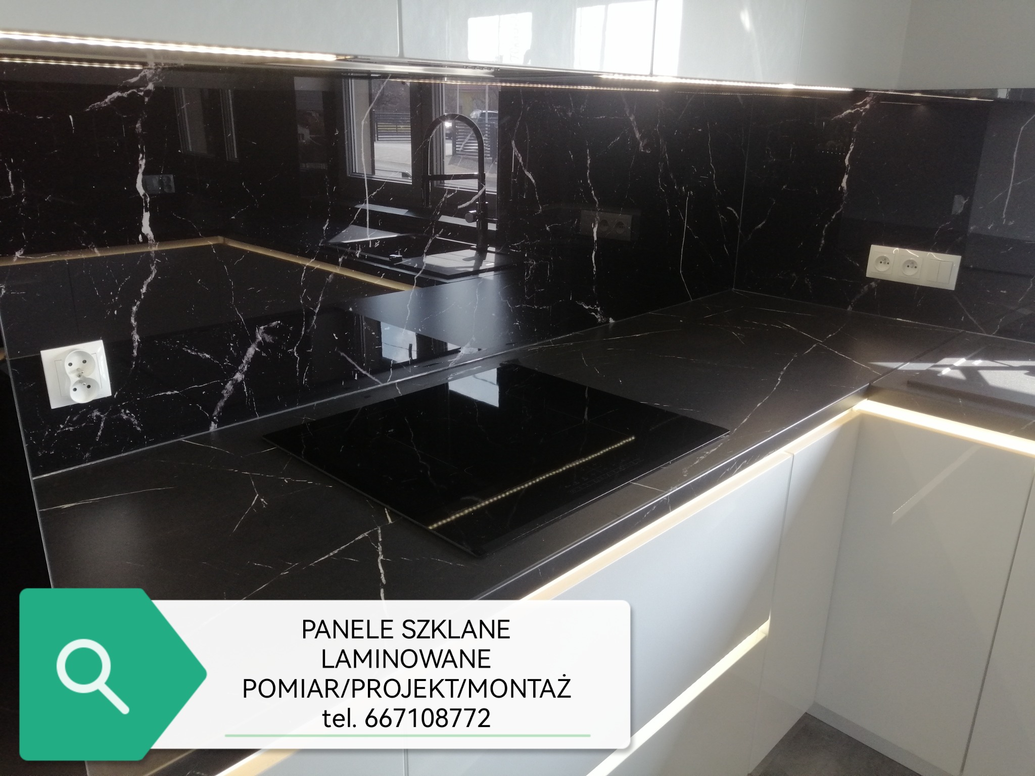 Część blatu kuchennego z czarnego marmuru z białymi żyłami, z wbudowaną płytą indukcyjną i zlewozmywakiem, oświetlona listwą LED pod szafkami wiszącymi.