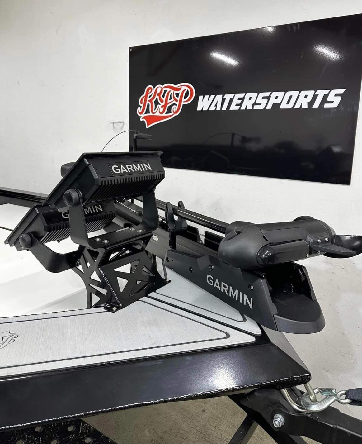 Czarny, metalowy uchwyt silnika elektrycznego Garmin zamontowany na łodzi, z widocznym logo KTP Watersports w tle.