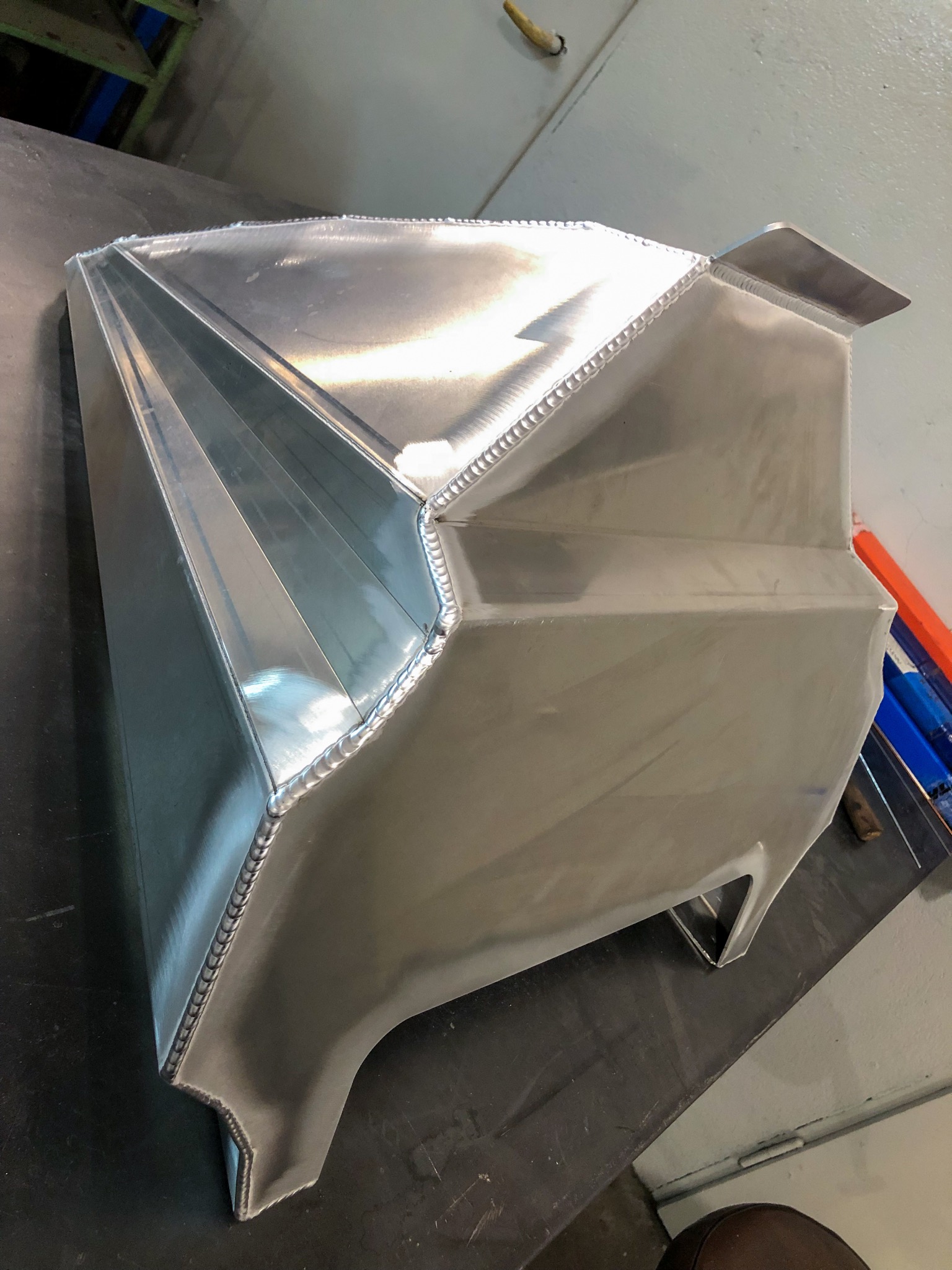 Konstrukcja zespawana z blachy aluminiowej o złożonej geometrii, widoczne spoiny spawalnicze, leżąca na stole warsztatowym w hali produkcyjnej.