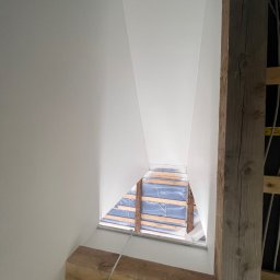 Dam-bud - Świeżo pomalowane, białe poddasze ze skośną ścianą i drewnianą konstrukcją nośną widoczną w otworze okiennym.