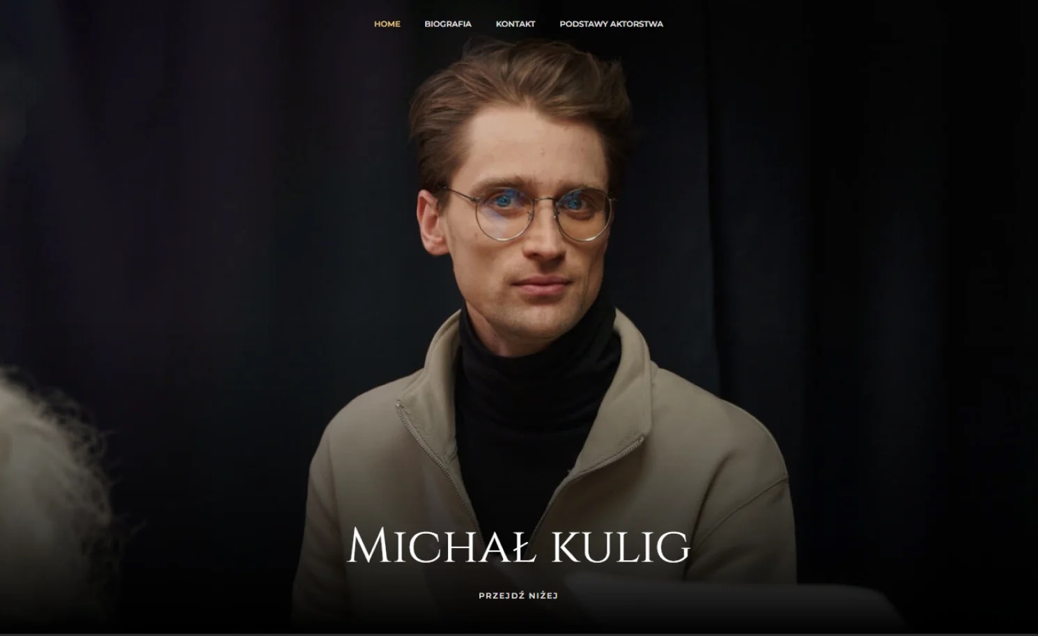 Strona internetowa z portretem mężczyzny w okularach na ciemnym tle, widoczne menu nawigacyjne u góry.