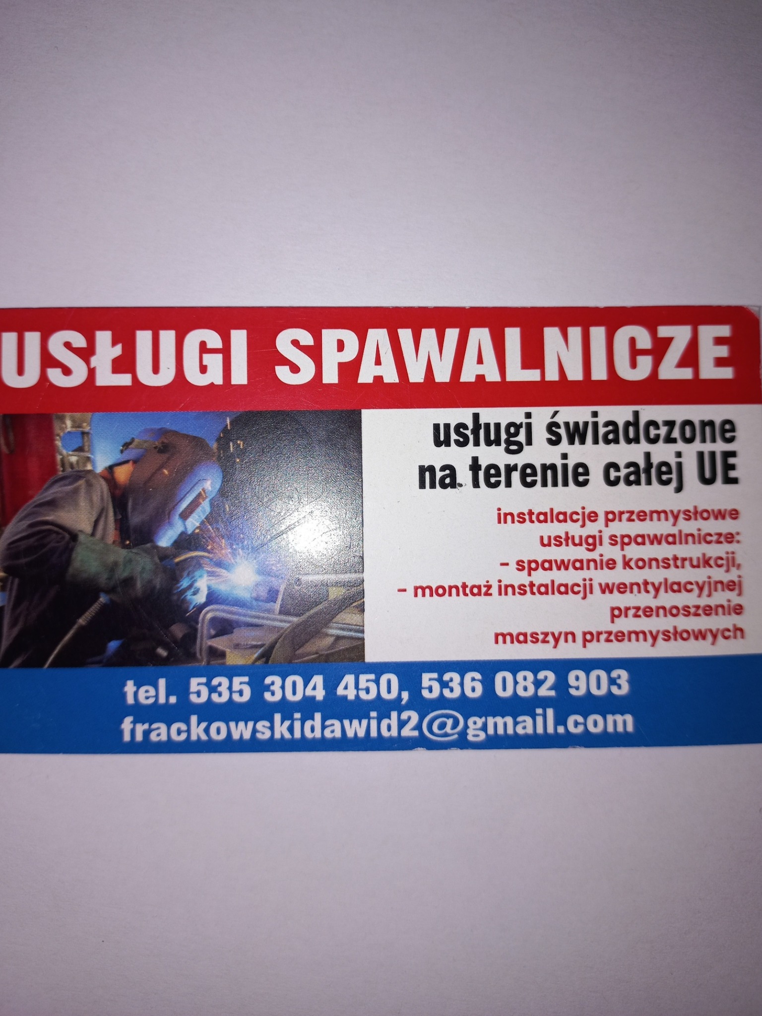 Wizytówka firmy oferującej usługi spawalnicze na terenie UE, z numerami telefonów i adresem e-mail. Na wizytówce widnieje zdjęcie spawacza w trakcie pracy.
