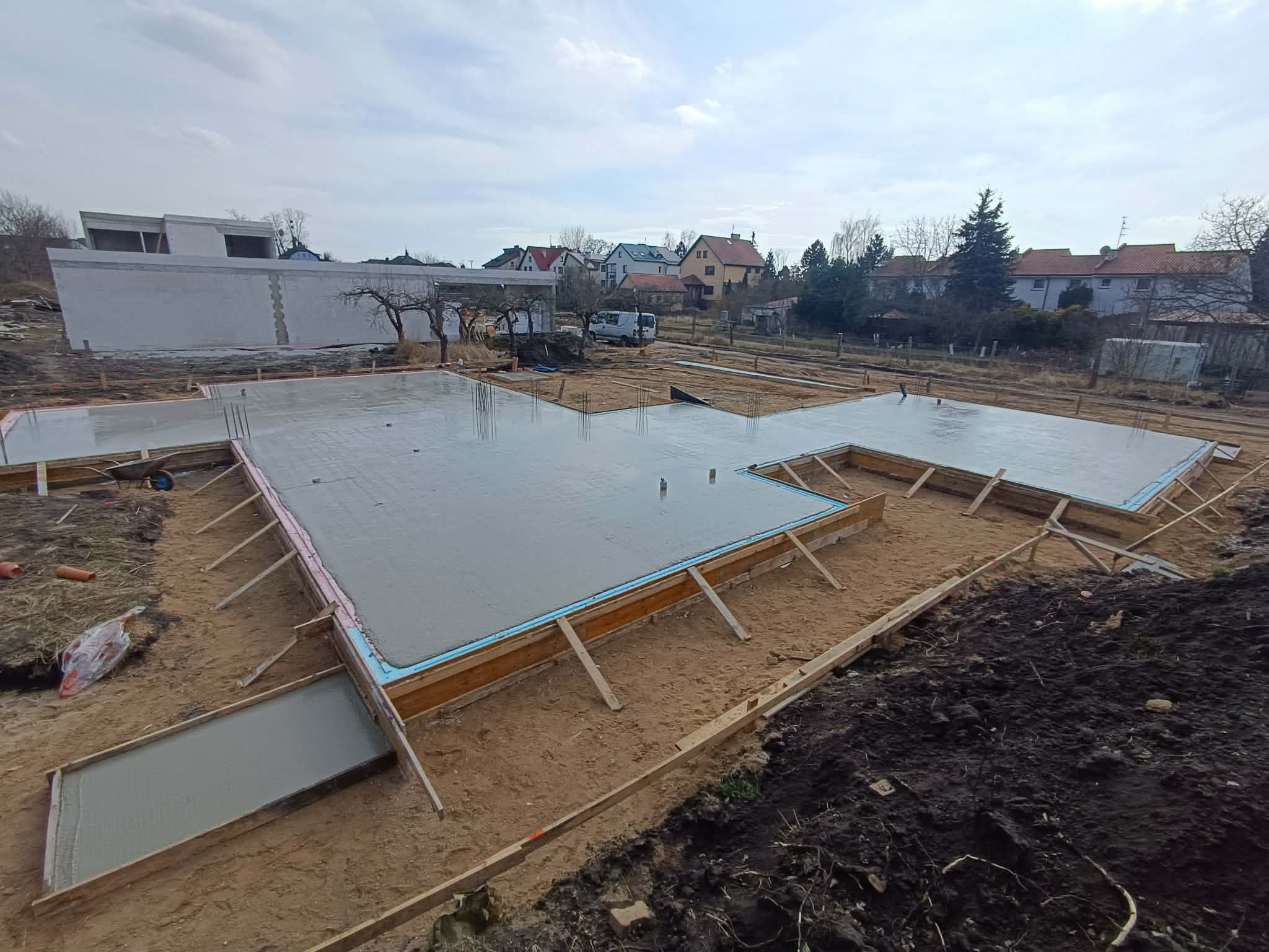 Zalane fundamenty pod budowę domu jednorodzinnego w Bielinach. Widoczne szalunki i izolacja termiczna. Świeży beton tworzy gładką powierzchnię.