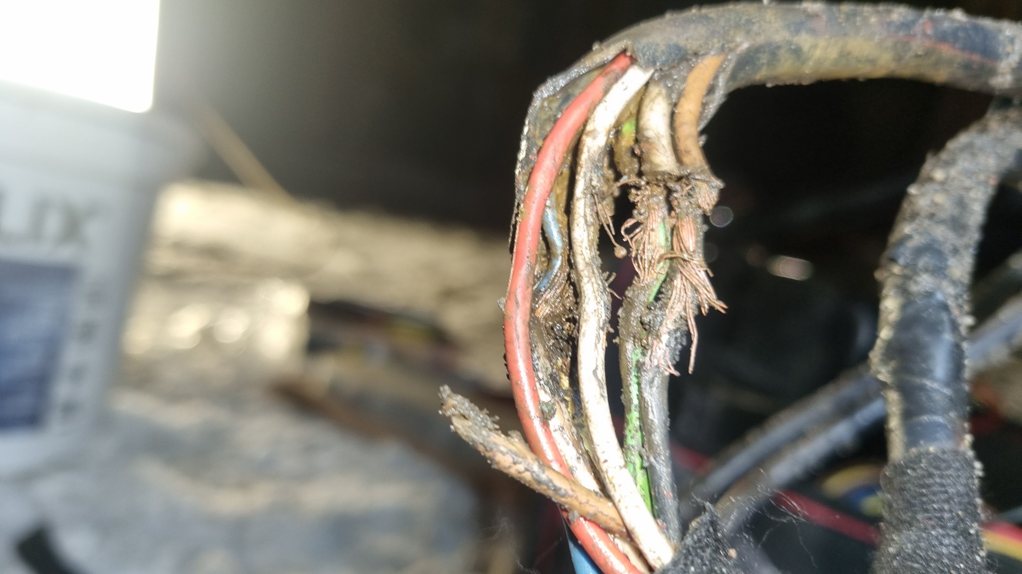 Uszkodzony kabel elektryczny z widocznymi przerwami w izolacji i zabrudzeniami, ukazujący zużycie i potencjalne zagrożenie.