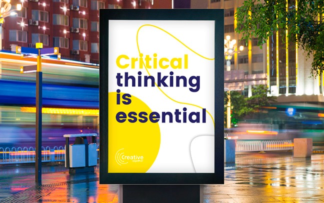 Billboard z hasłem 'Critical thinking is essential' na tle nocnego miasta z rozmytymi światłami przejeżdżających pojazdów i mokrym chodnikiem.