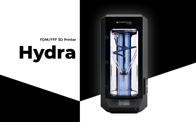 Czarna drukarka 3D Innovatica Hydra FDM/FFF z widoczną niebieską spiralą wewnątrz komory roboczej, na czarno-białym tle.