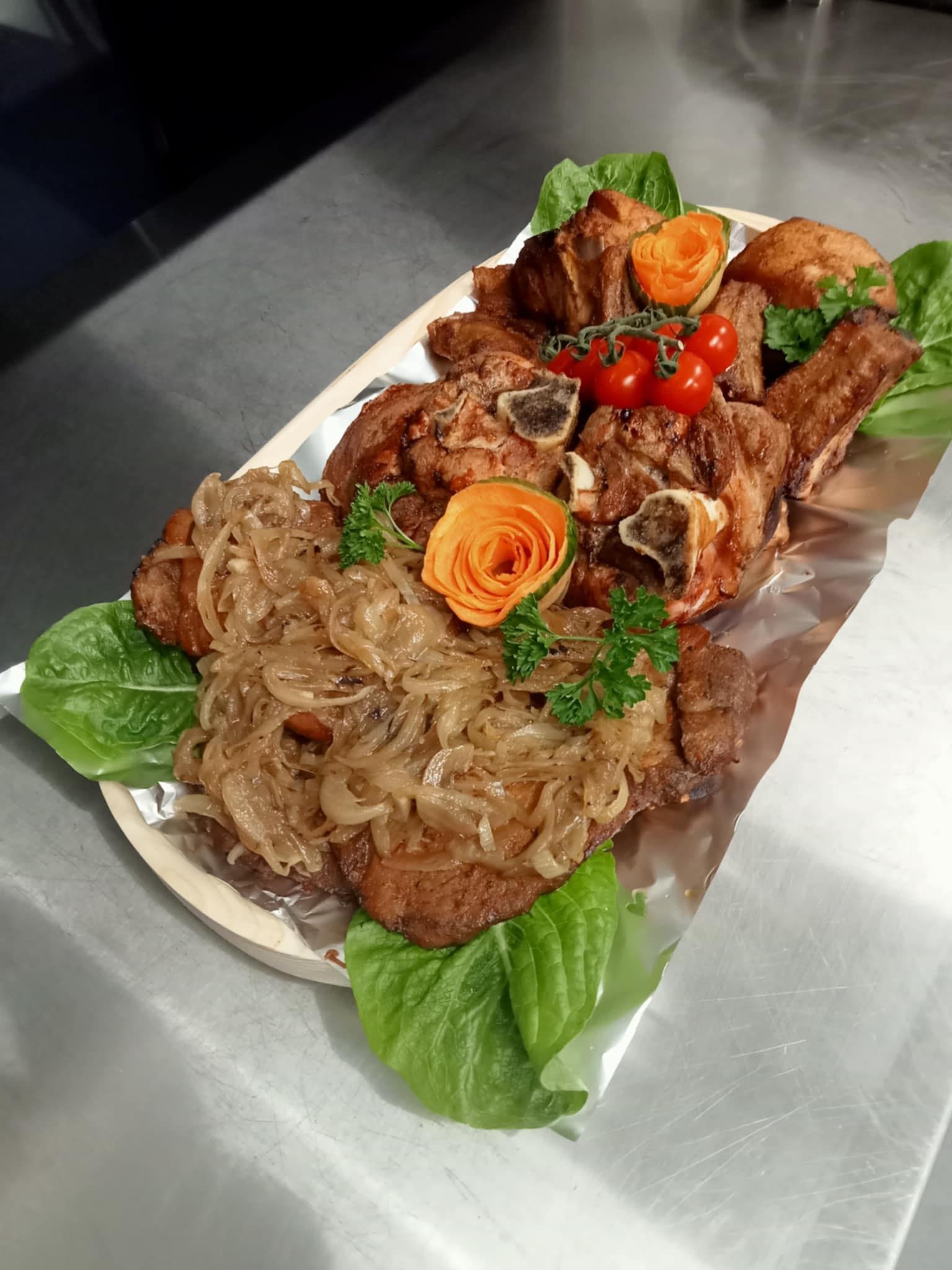 Taca z pieczonym mięsem, udekorowana karmelizowaną cebulą, pomidorkami cherry, natką pietruszki i liśćmi sałaty, z ozdobną rozetką z marchewki.