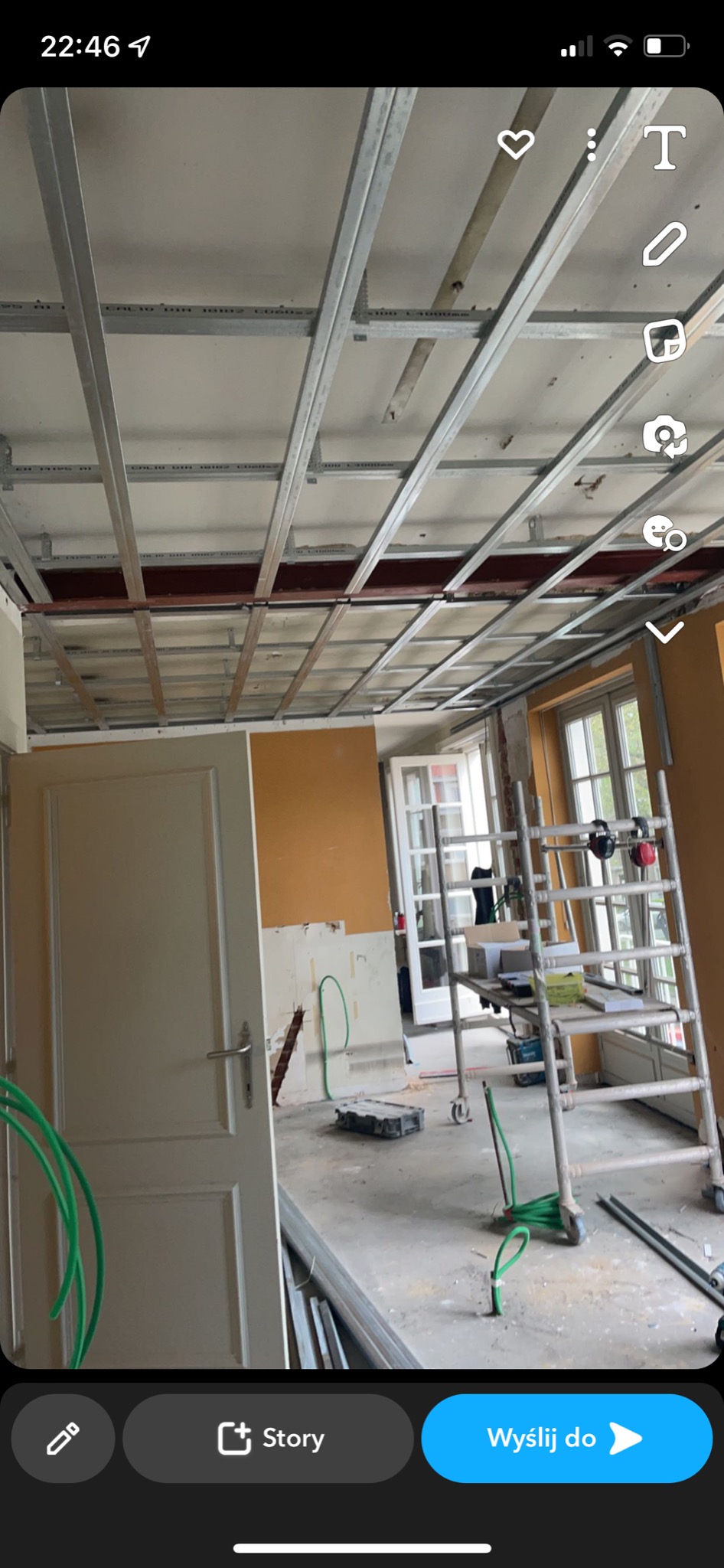 Montaż metalowej konstrukcji podwieszanego sufitu w trakcie remontu mieszkania, widoczne profile, drabina i fragmenty instalacji.