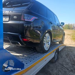 My dreams Justyna Kowalewska - Czarny Range Rover Sport na platformie pomocy drogowej, widok z tyłu, srebrne felgi, tablica rejestracyjna, słoneczny dzień, teren poza miastem.