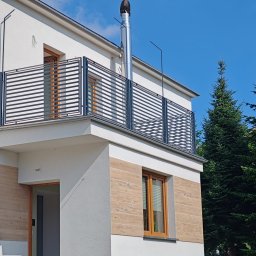 FOCUS WELD Sylwester Wasilewski - Nowoczesna balustrada balkonowa z poziomych profili metalowych, zamontowana w nowym domu z jasną elewacją i elementami dekoracyjnymi imitującymi drewno.