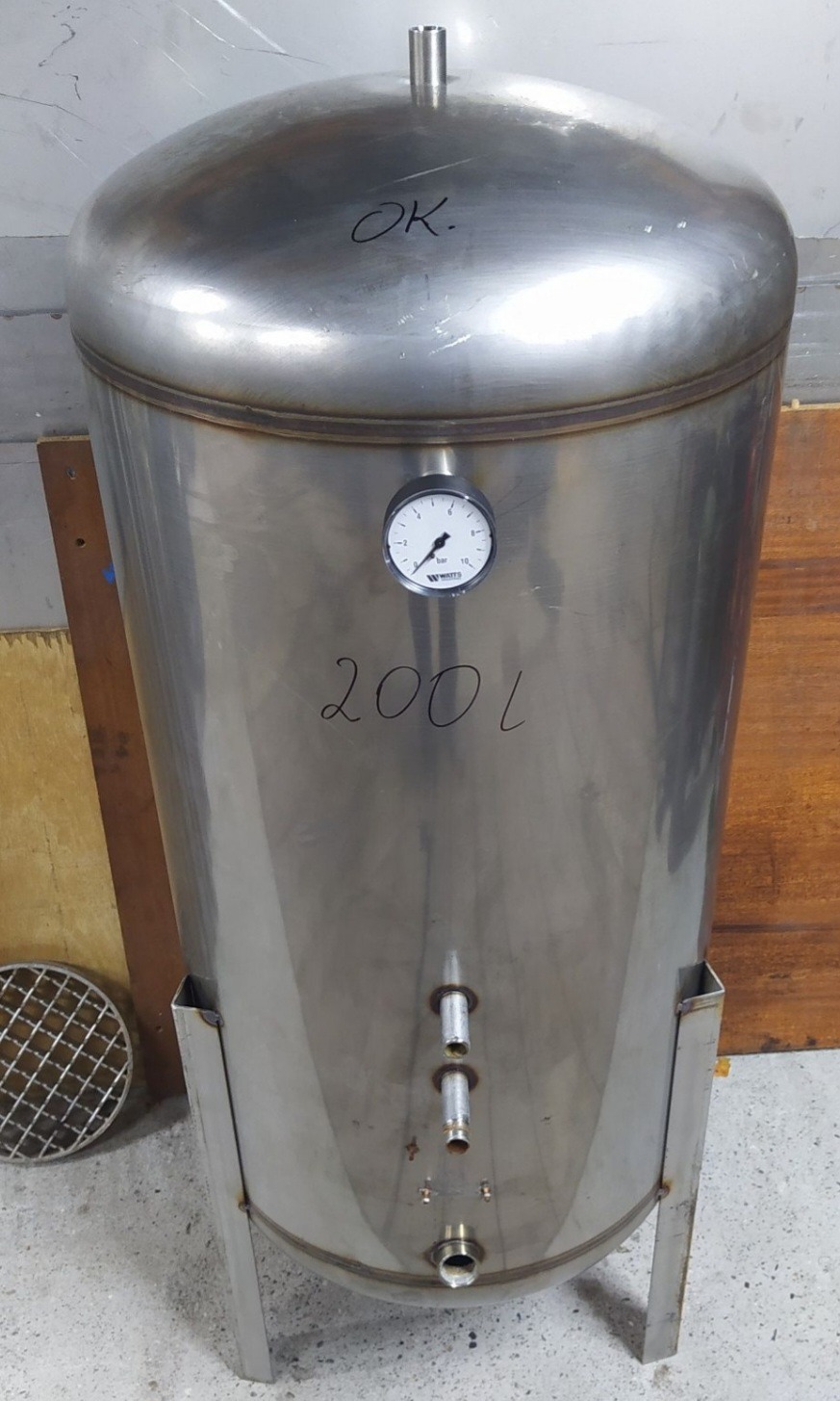Stalowy zbiornik o pojemności 200 litrów z manometrem i trzema króćcami, spawany na stojaku, z napisem 'OK' na górze.