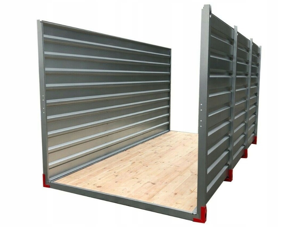 Wnętrze kontenera magazynowego z drewnianą podłogą i szarymi, żebrowanymi ścianami z metalu, widoczne czerwone narożniki podstawy.