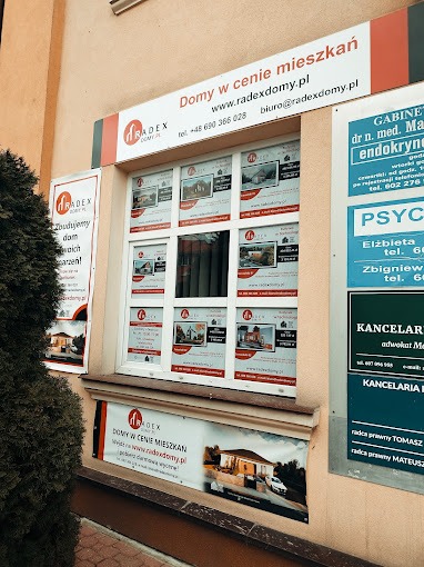 Biuro firmy budowlanej Radexdomy.pl z reklamami domów w oknach i na banerach.