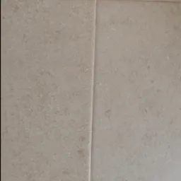 Beżowe płytki podłogowe z delikatną teksturą i fugami w zbliżeniu.