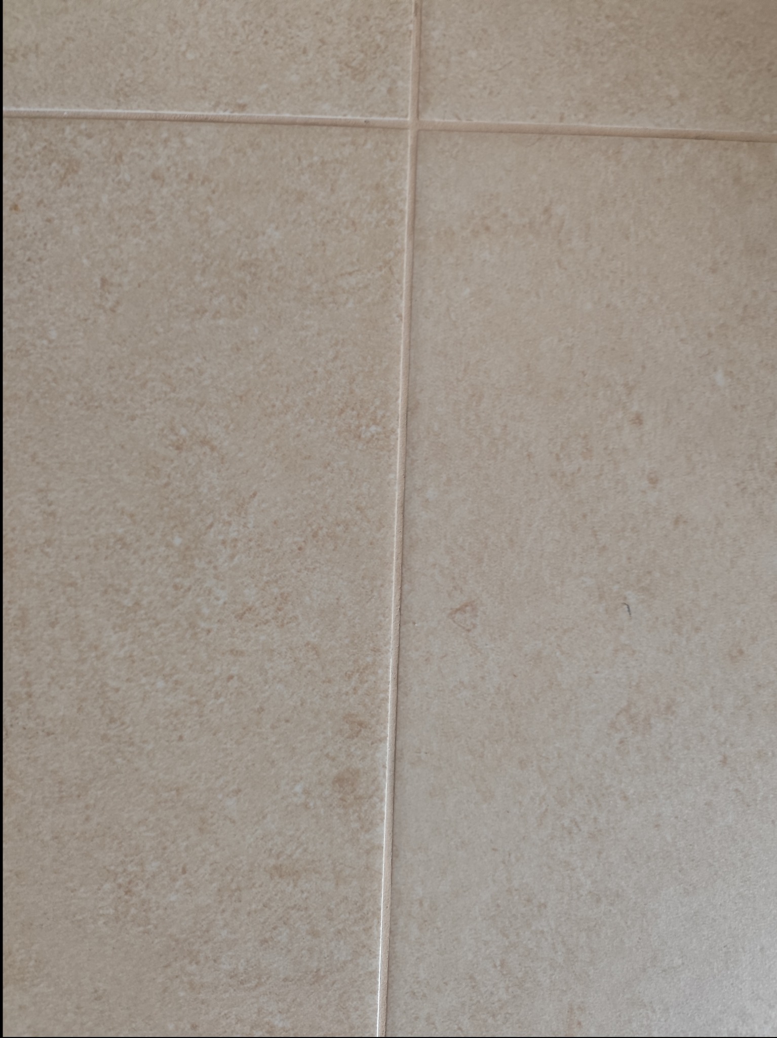 Beżowe płytki podłogowe z delikatną teksturą i fugami w zbliżeniu.