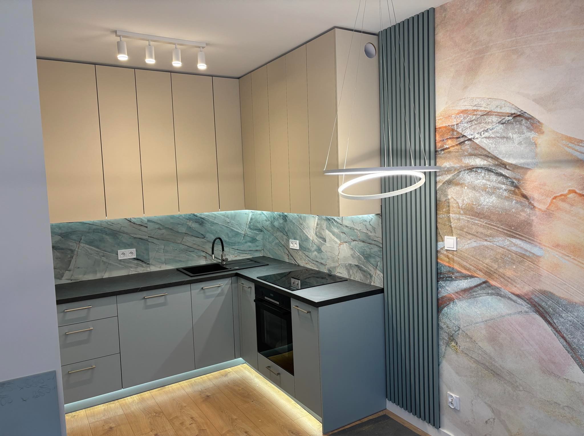 Nowoczesna kuchnia w odcieniach beżu i szarości z marmurowym backsplashiem, oświetleniem LED pod szafkami i abstrakcyjnym malowidłem na ścianie