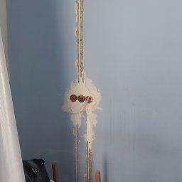 MORAS TOMASZ MORAWSKI - Ściana w trakcie remontu z widocznymi przewodami elektrycznymi w bruzdach i puszkami pod gniazdka, przygotowana do dalszych prac wykończeniowych.