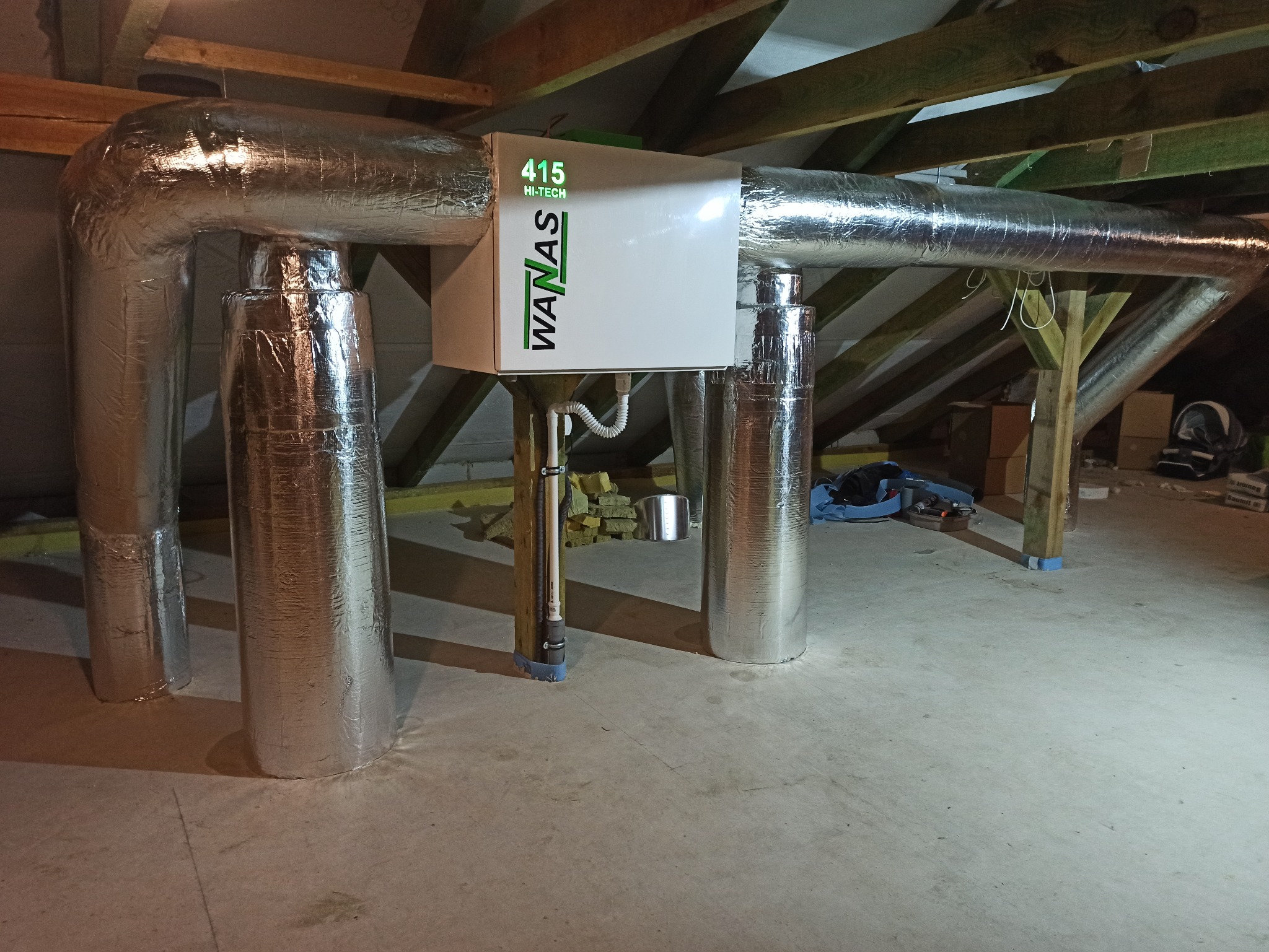 Centrala rekuperacyjna WanAs 415 Hi-Tech z izolowanymi przewodami wentylacyjnymi w przestrzeni poddasza, widoczne elementy konstrukcji dachu.