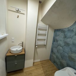 Remonty SAV-REM - Nowoczesna łazienka z umywalką nablatową na szafce z szufladami, grzejnikiem drabinkowym i ścianą wyłożoną heksagonalnymi płytkami w odcieniach szarości i błękitu.